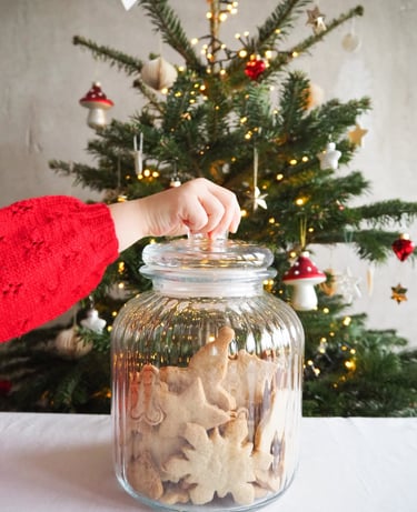 ciasteczka w szklanym słoju na tle zielonej choinki, ręka sięga do słoika