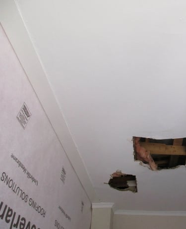 Hole in ceiling showing roof board failure