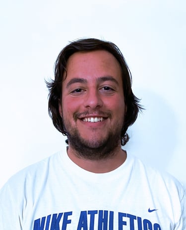 Rafael Botelho with a beard smiling while wearing a white t-shirt