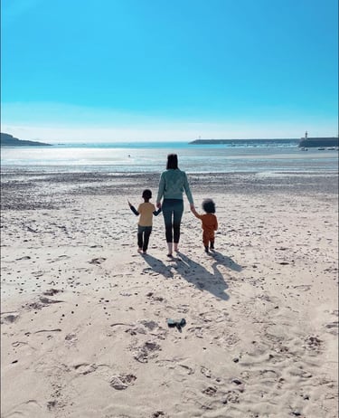 a woman and two children walking on a beach