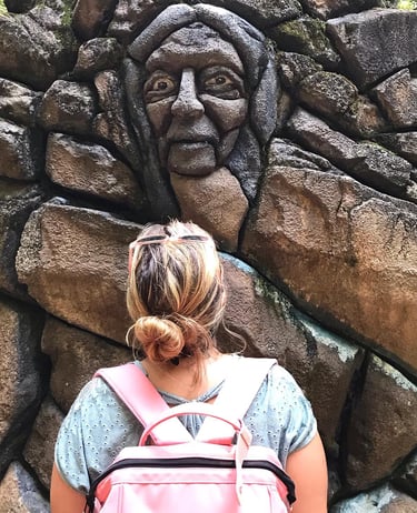 a woman with a backpacker in front of a stone wall