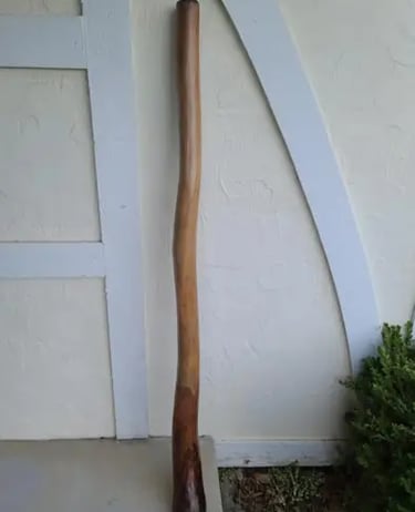 a didgeridoo leaning against a house wall made from fibro and timber