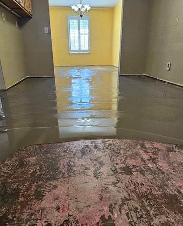 Interior room with freshly poured self-leveling concrete flooring during renovation.