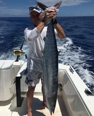 Un client tenant un thon banane par la queue sur le bateau
