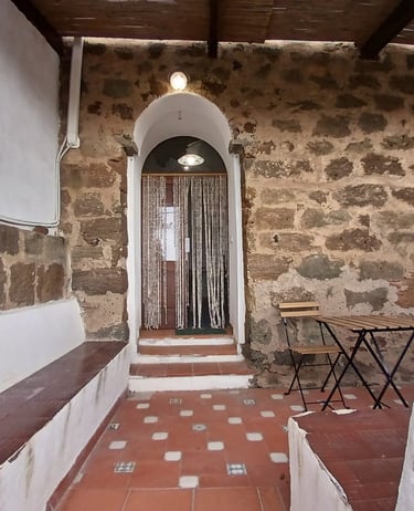 Entrance of a dammuso in Rekhale with stone arch, beaded curtain and tiled patio