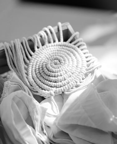 Handmade off-white cotton rope trivet or coaster with spiral design and fringe.