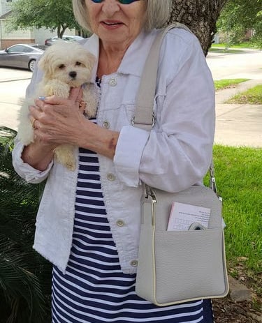 White Maltese Puppy with lady stangding under tree.