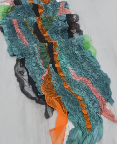Handmade nuno felt scarf featuring layered green silk and vibrant orange silk ruffles
