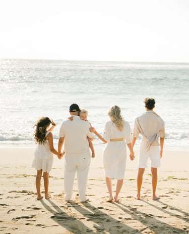 Family seen from behind walking toward the ocean during a family photography session at Ayodya Resort Bali