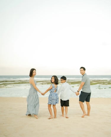 Family walking together along the shoreline during a luxury family photography session at The Ritz-Carlton Bali.