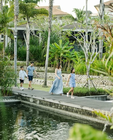 Family walking beside a reflecting pond during a luxury family photography session at The Ritz-Carlton Bali.
