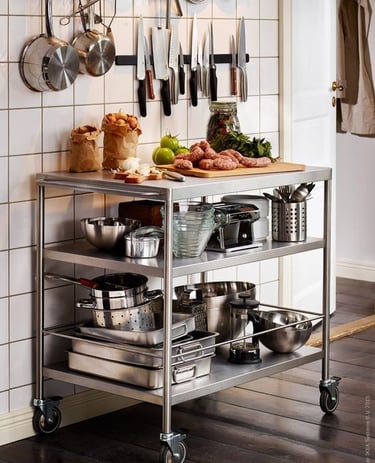 Mobile kitchen island with Stainless Steel Benchtops and two shelves, holding various cooking items.