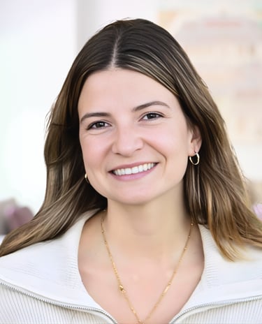 Smiling woman with brown hair wearing a white sweater and gold jewelry in a bright professional headshot.