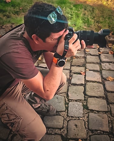 Photographe concentré, accroupi sur des pavés, appareil photo à la main, capturant une scène avec précision et passion
