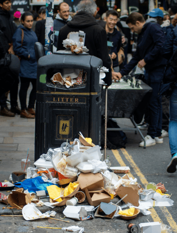 person standing beside garbage bin