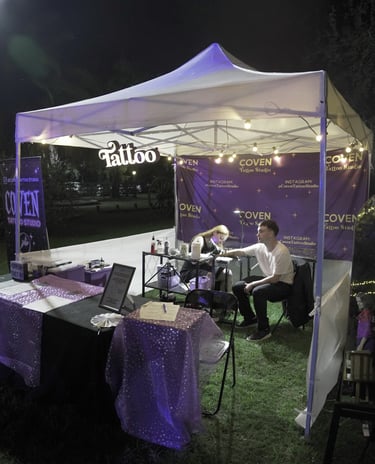 Invitado recibiendo un tatuaje real en el stand profesional de Coven Tattoo Studio en un evento