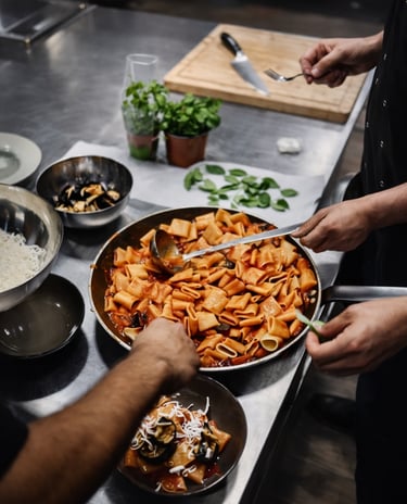 Chefs en cuisine professionnelle dressant un plat de rigatoni, capturé dans le cadre d’un reportage 