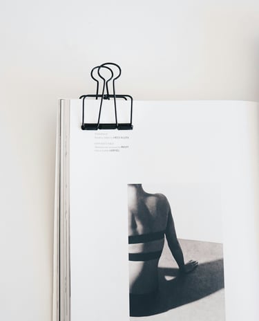 Un clip noir maintient ouvert un magazine de photographie minimaliste présentant une photo éditorial