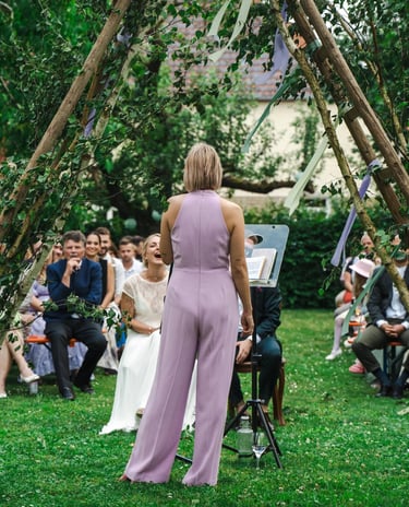 Traurednerin Silke leitet eine freie Trauung im Freien vor einem Hochzeitspaar und den versammelten Gästen.