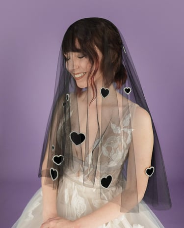 Bride wearing a black wedding veil with velvet hearts on it outlined in pearls