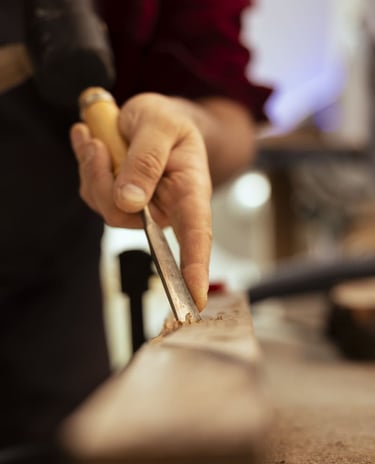 Artesano experto en carpintería utilizando un cincel metálico afilado para tallar detalles en madera