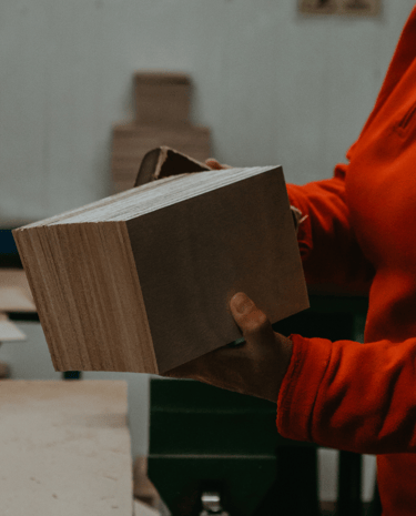 a woman in a red shirt is holding a couple of quality wood pieces