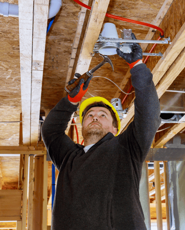 Electrician wearing a hardhat, installing new recessed lights at a business in Early Tx