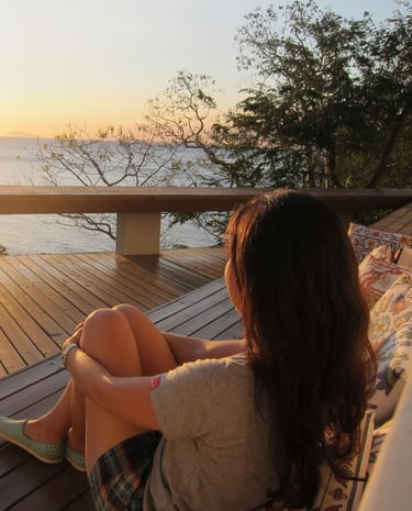 a woman sitting on a couch with a view of the ocean