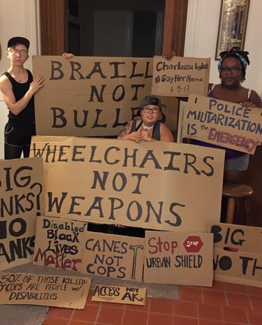 Photo of Stacey with Friends displaying posters they made in protest of Urban Shield and supporting BLM.