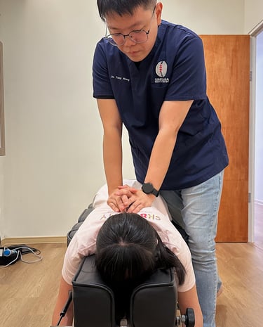 Chiropractor performing manual back adjustment on female patient at Sinisana Chiropractic clinic.