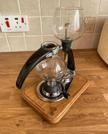 a coffee maker with a glass carafeine on a wooden stand
