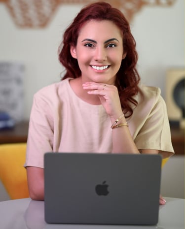 Psicóloga Palloma D'Andrade sorrindo enquanto trabalha com terapia online