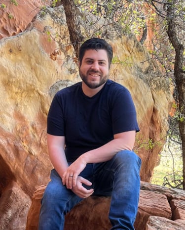 Christopher Carpenter sitting on a rock formation in the Utah mountains.