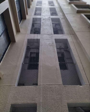 Technician from Arjilli Enterprises securing duct area nets to apartment building.