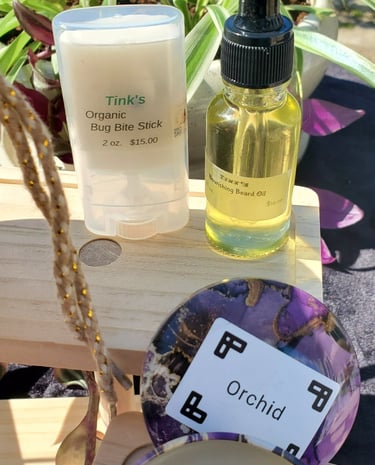 Handmade organic bug bite stick, nourishing beard oil, and an orchid scented candle on display