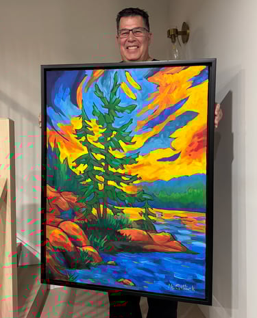 Mitch Gillick holding a painting of a Muskoka sunset