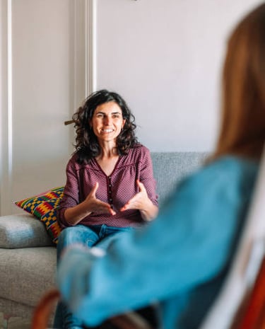 smiling woman with dark hair holding her hands in front of her body is facing person