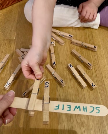 Child matching alphabet wooden clothespins to a craft stick for a preschool literacy activity.