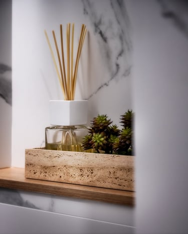 Un jarrón con una planta y un ambientador en un estante.