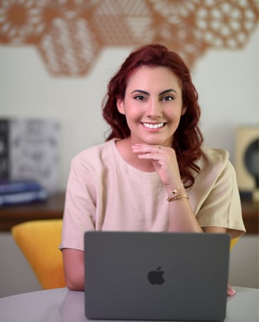 Psicóloga Palloma D'Andrade sorrindo enquanto trabalha com terapia online
