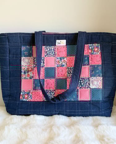 Handmade quilted denim tote bag featuring a pink and blue floral patchwork panel design.
