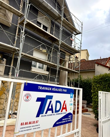Chantier pose isolant sur façade avec échafaudage et pancarte TADA 
