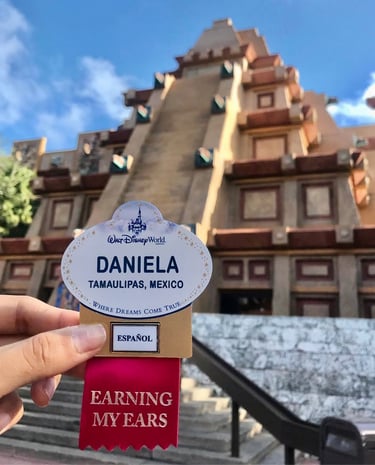 Mano sosteniendo name tag de Disney World frente a la pirámide de México en EPCOT