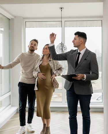 A real estate agent showing a modern new apartment to a young pregnant couple.