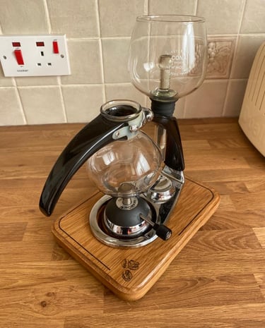 a coffee maker with a glass carafeine on a wooden stand