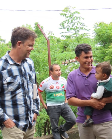 A man holds a baby, while another looks one smiling