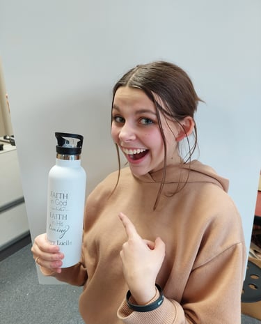 a woman in a brown sweater holding a water bottle