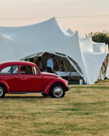 Vintage red Volkswagen Beetle parked on a grassy field in front of  our marquees