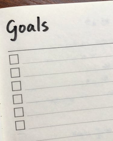 A closeup of a notepad with blurry text of goals and check marks
