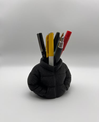 Creative black puffer jacket pen holder for desk organization featuring assorted pens and markers.